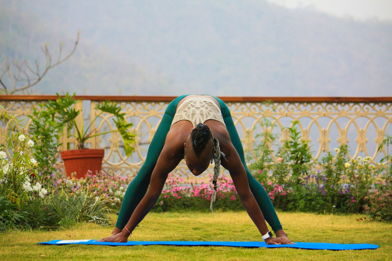 Home Woman practicing yoga outdoors in a lush garden in Rishikesh, India.